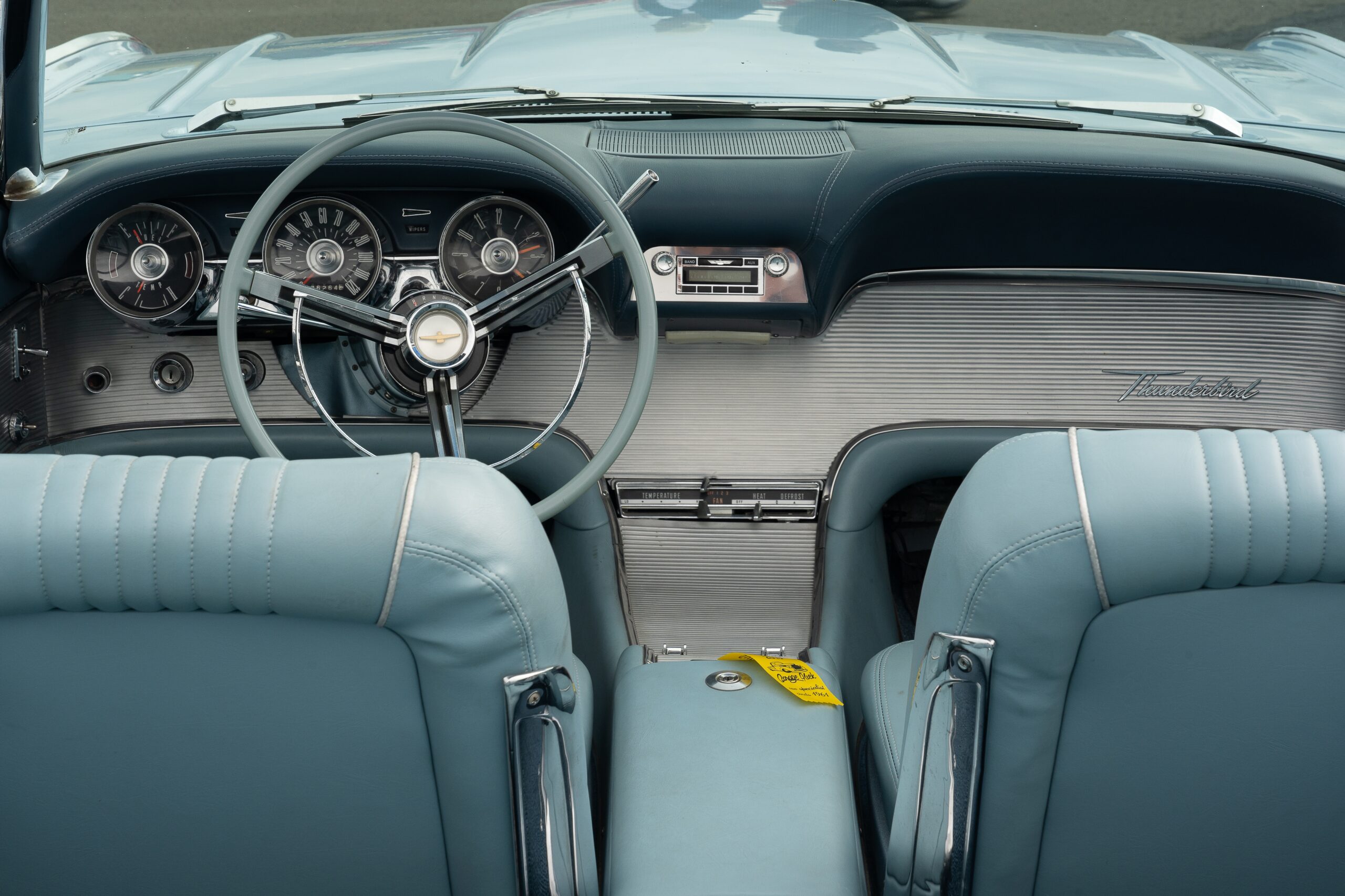 A closeup shot of the light blue interior of a car, including the seats and the steering wheel